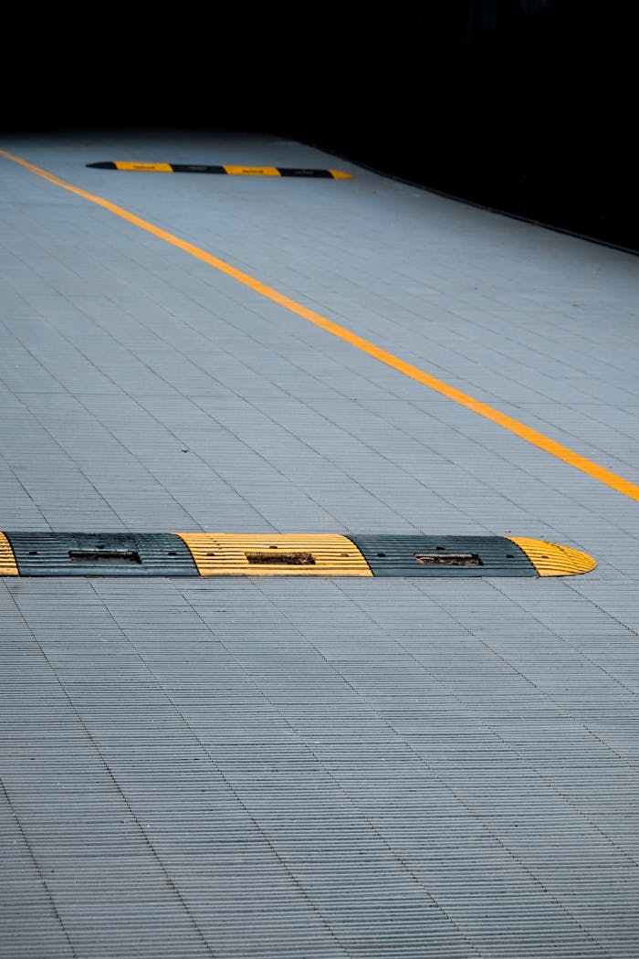 Yellow and black speed bumps on a gray urban pavement with clear lines marking the parking area.